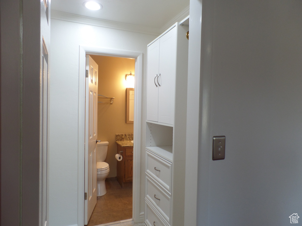 Bathroom featuring tile patterned flooring, vanity, ornamental molding, and toilet