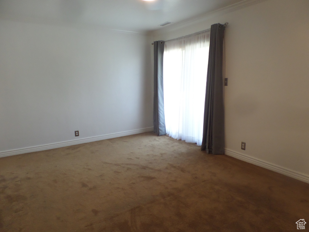 Unfurnished room with carpet floors, baseboards, and crown molding