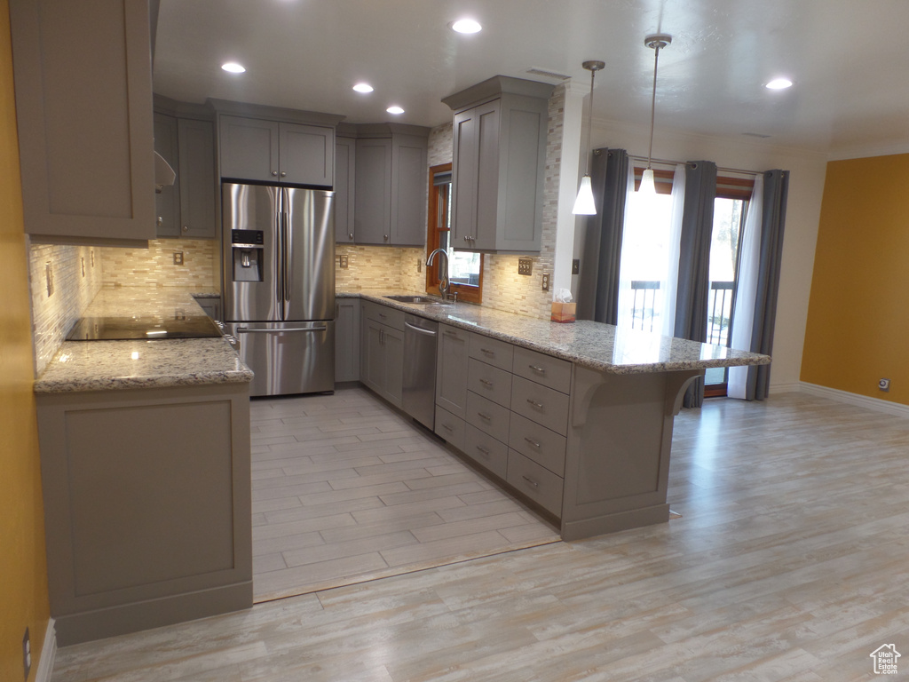 Kitchen with appliances with stainless steel finishes, pendant lighting, sink, a breakfast bar area, and kitchen peninsula