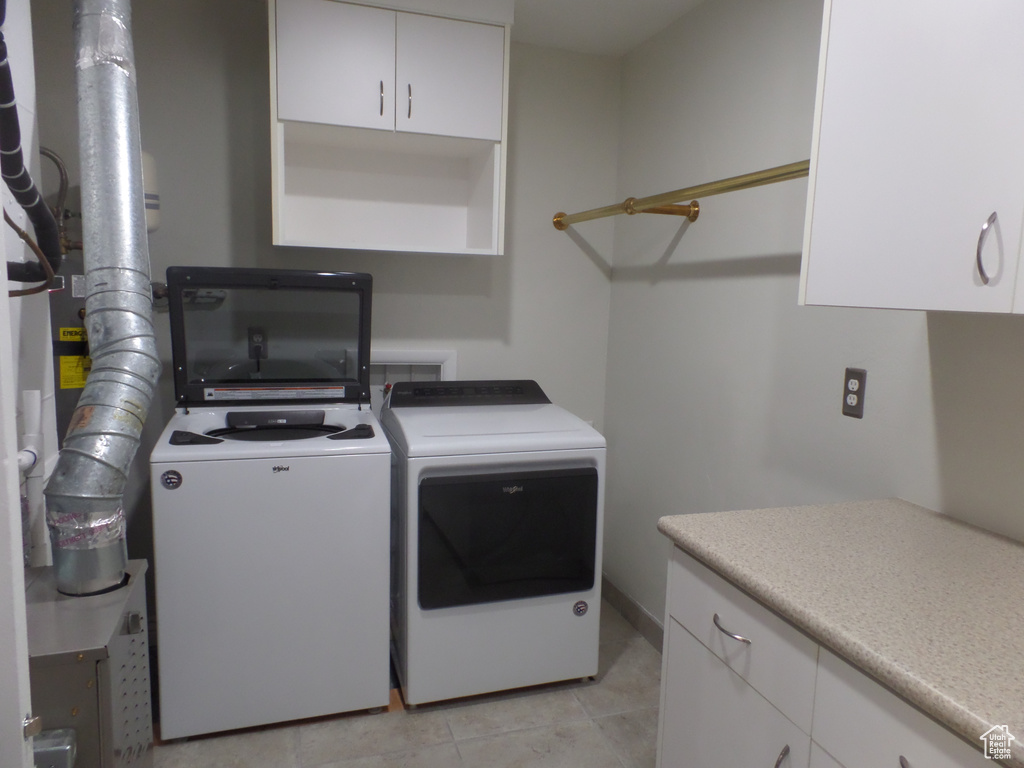 Washroom featuring cabinets, light tile patterned flooring, and washing machine and clothes dryer