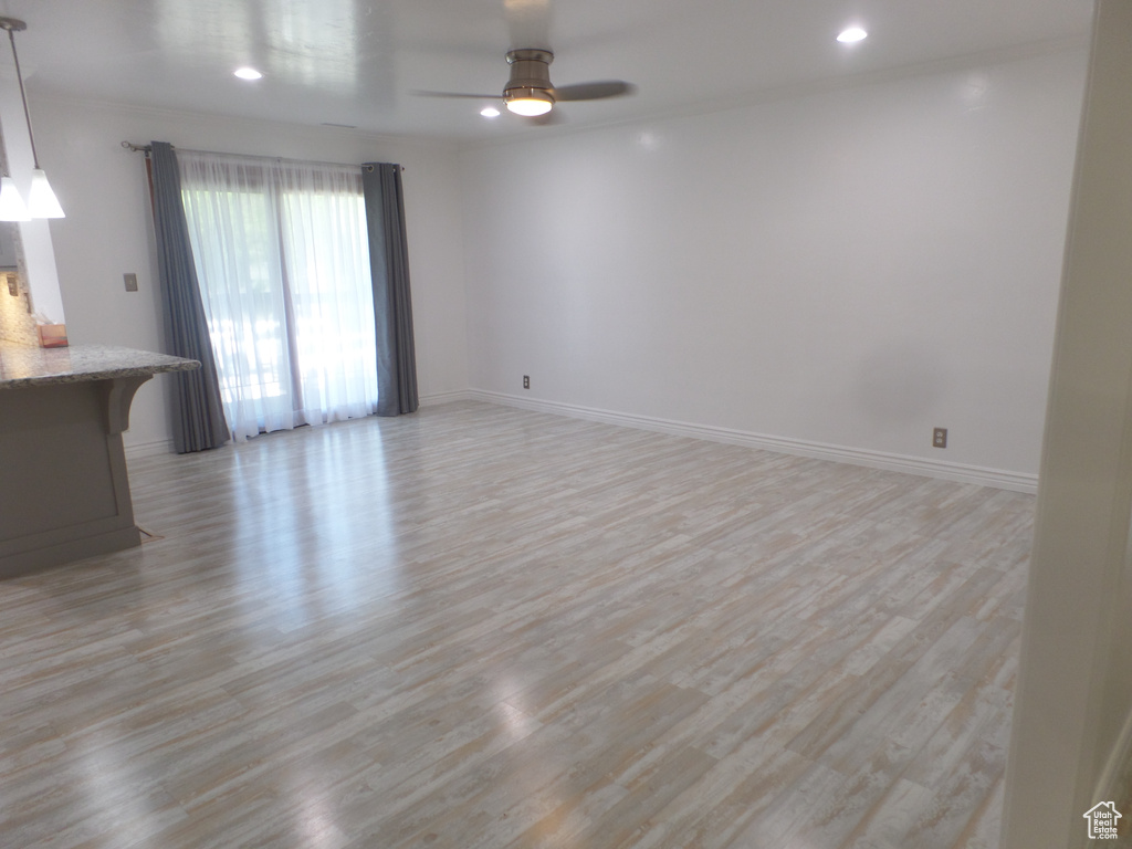 Unfurnished living room with light wood finished floors, ceiling fan, baseboards, and recessed lighting