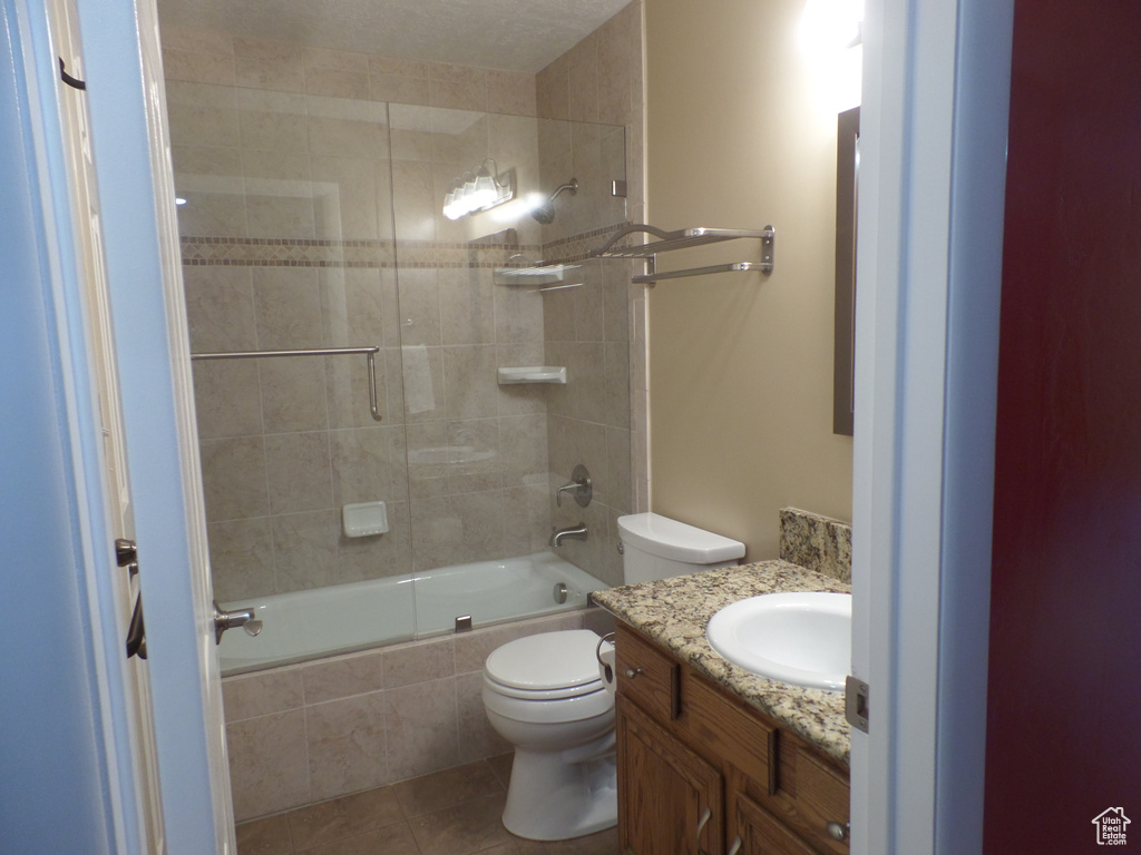 Full bathroom with vanity, combined bath / shower with glass door, tile patterned floors, and toilet