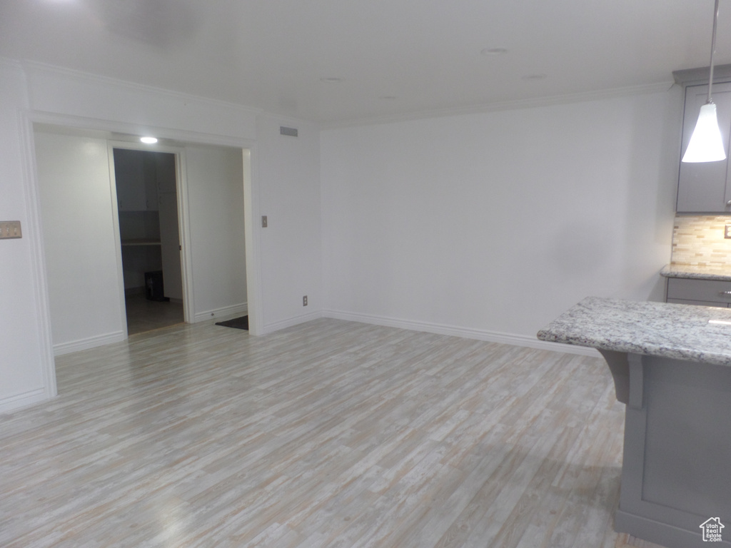 Empty room with light wood-type flooring, crown molding, and baseboards