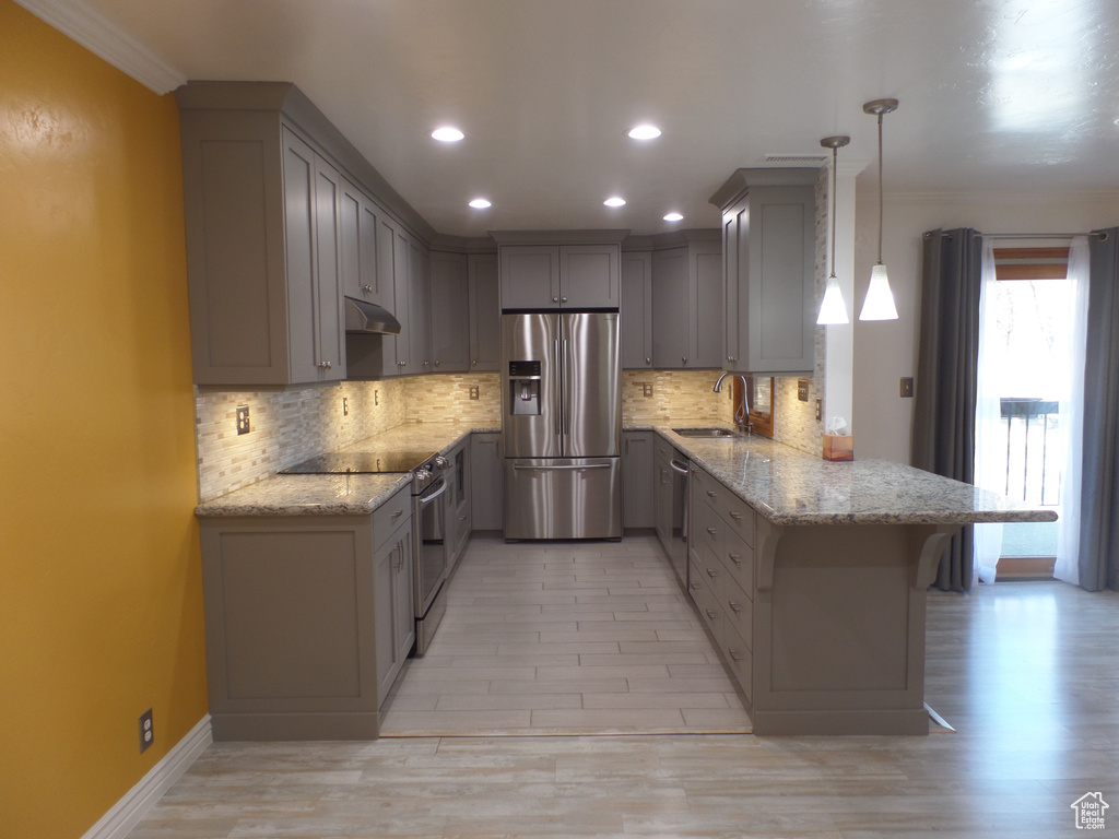 Kitchen with appliances with stainless steel finishes, decorative light fixtures, sink, gray cabinetry, and kitchen peninsula