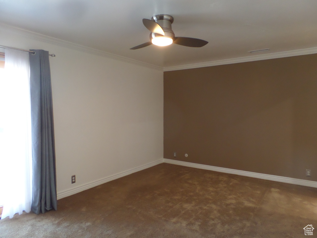 Empty room with ornamental molding, ceiling fan, and carpet