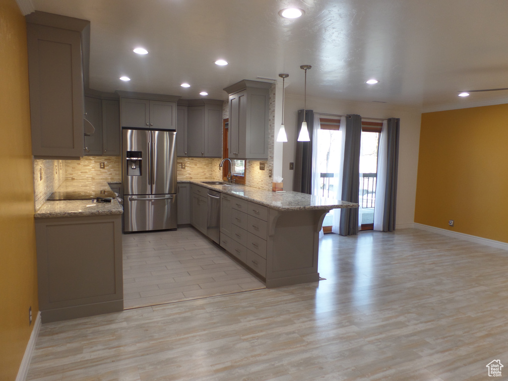 Kitchen with sink, decorative light fixtures, appliances with stainless steel finishes, kitchen peninsula, and gray cabinets