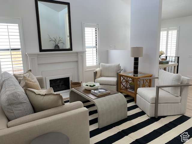 Living room with healthy amount of natural light, a fireplace with flush hearth, and wood finished floors