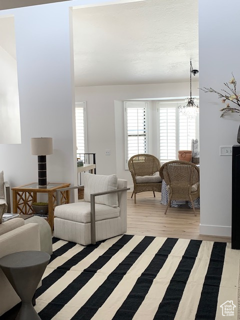 Living room featuring plenty of natural light, a chandelier, and light wood-style flooring