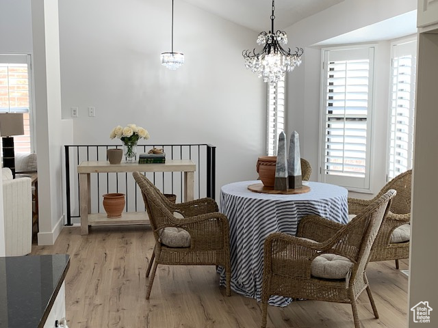 Dining area with healthy amount of natural light, light wood-style floors, a chandelier, and vaulted ceiling