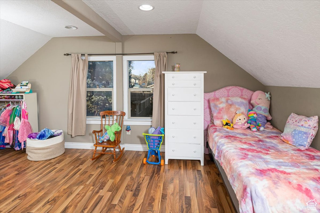 Bedroom with lofted ceiling, dark hardwood / wood-style floors, and a textured ceiling