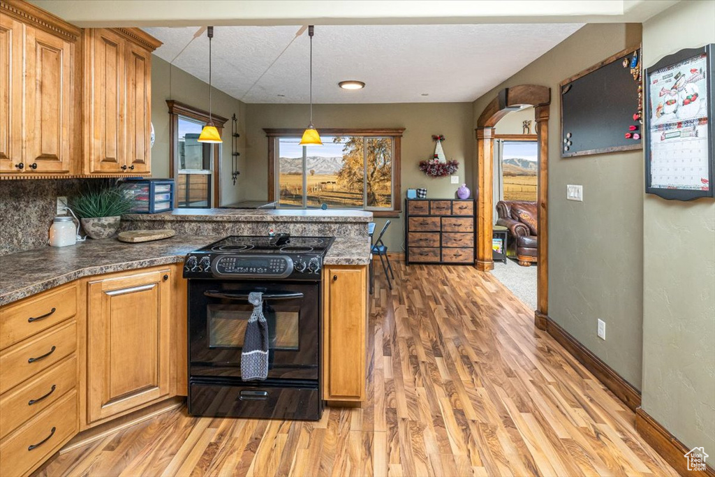 Kitchen featuring pendant lighting, black electric range oven, light hardwood / wood-style floors, and a healthy amount of sunlight