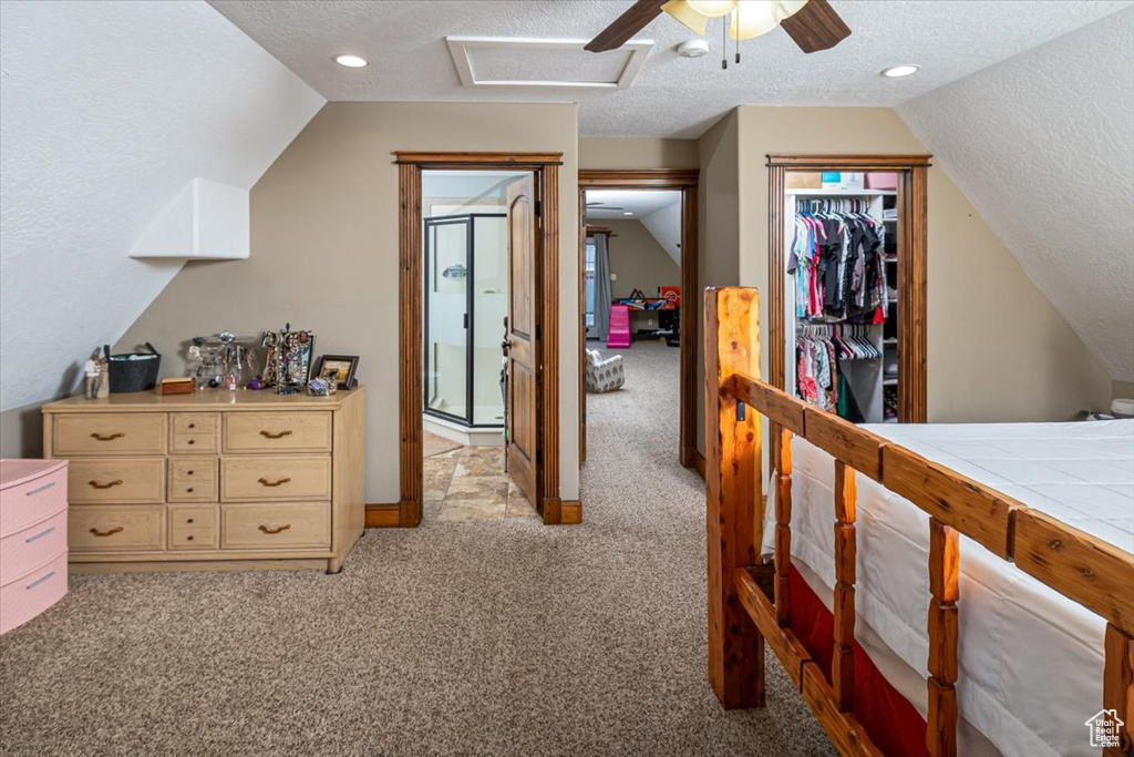 Bedroom featuring vaulted ceiling, light carpet, a textured ceiling, and a closet