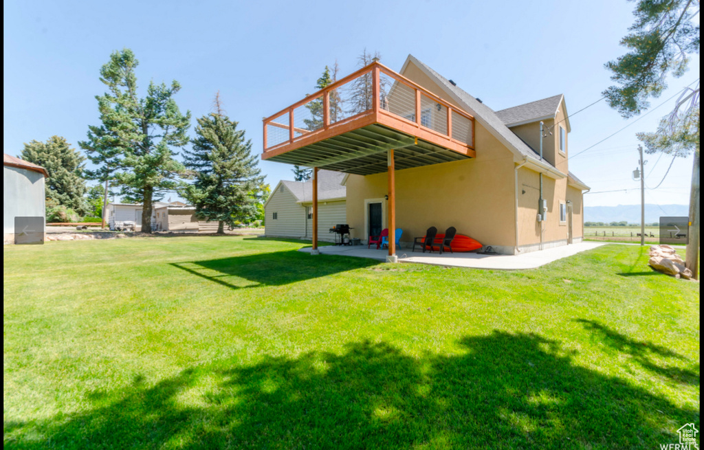 Rear view of house with a patio, a deck, and a lawn