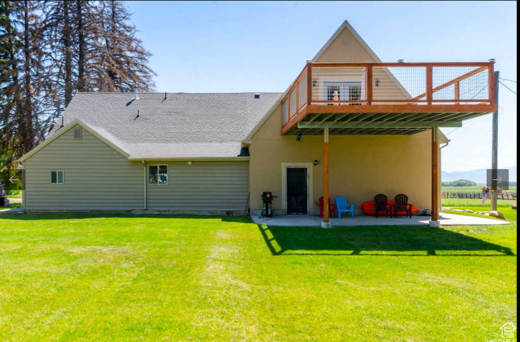 Back of property featuring a wooden deck, a yard, and a patio area