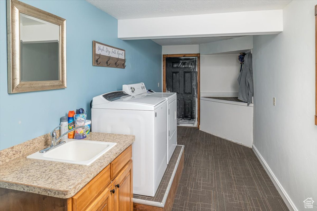 Washroom featuring separate washer and dryer, sink, and a textured ceiling