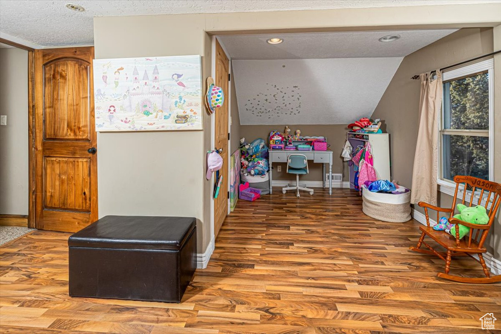 Bedroom featuring wood-type flooring, lofted ceiling, and a textured ceiling