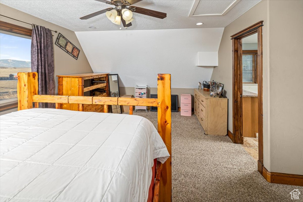 Bedroom featuring ceiling fan, vaulted ceiling, a textured ceiling, and carpet