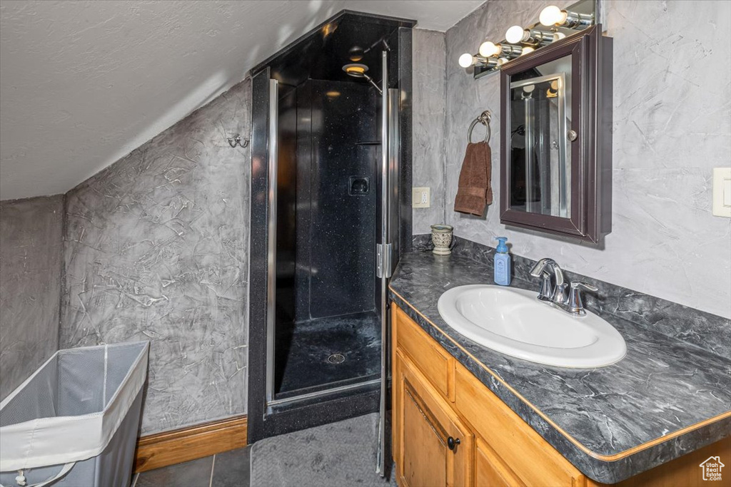 Bathroom featuring tile patterned floors, vanity, and vaulted ceiling