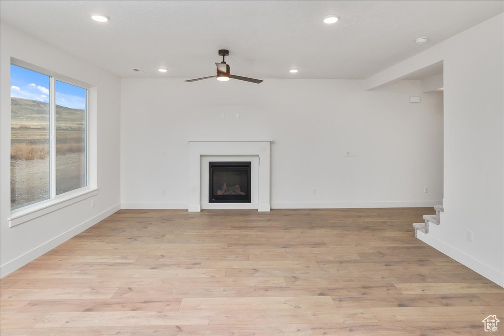 Unfurnished living room featuring ceiling fan and light wood-type flooring