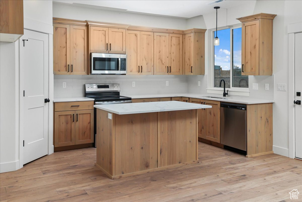 Kitchen featuring pendant lighting, tasteful backsplash, sink, stainless steel appliances, and light wood-type flooring