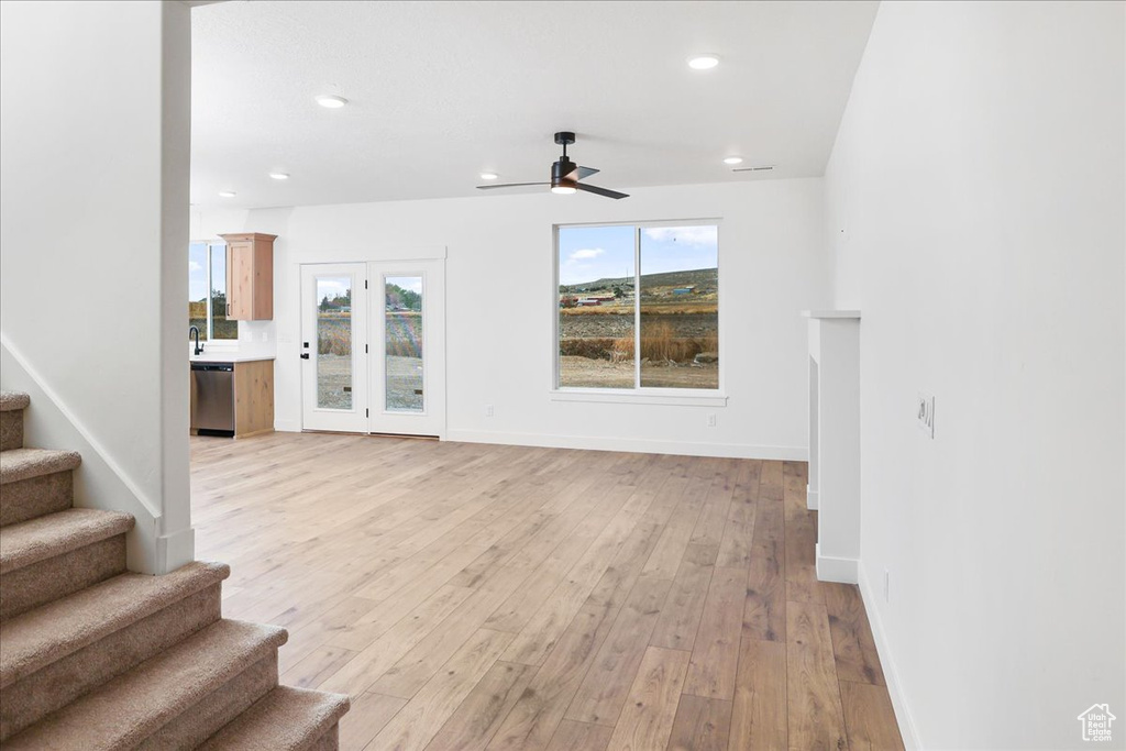 Unfurnished living room featuring ceiling fan and light hardwood / wood-style flooring