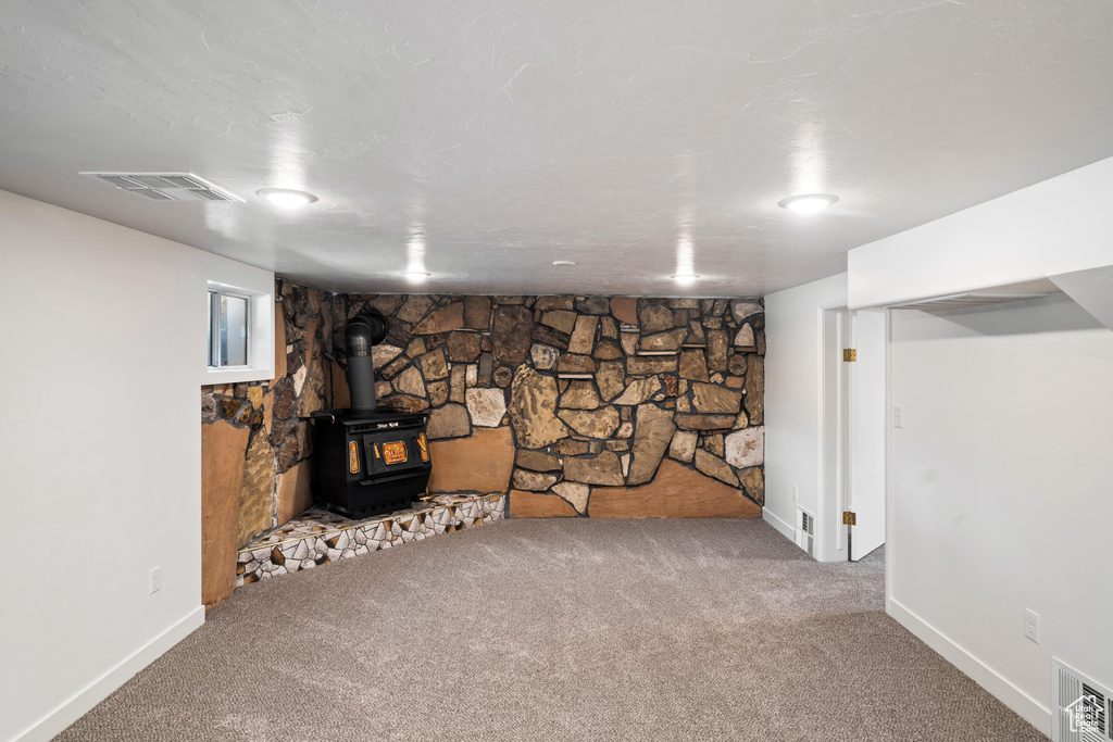 Basement featuring carpet and a wood stove