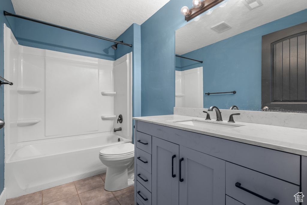 Bathroom with vanity, shower / washtub combination, toilet, tile patterned flooring, and a textured ceiling