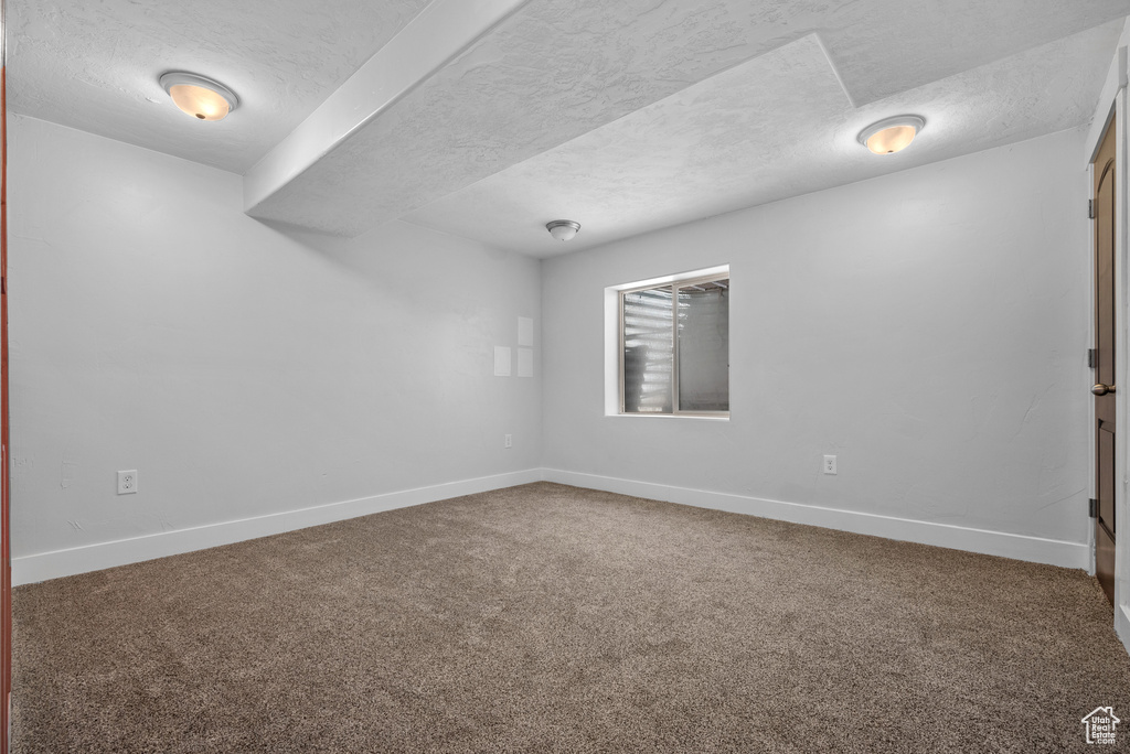 Unfurnished room featuring a textured ceiling, carpet flooring, and baseboards
