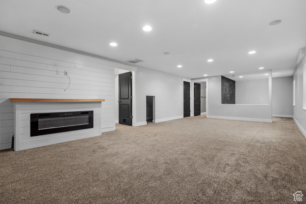 Unfurnished living room featuring recessed lighting, a glass covered fireplace, carpet flooring, and baseboards