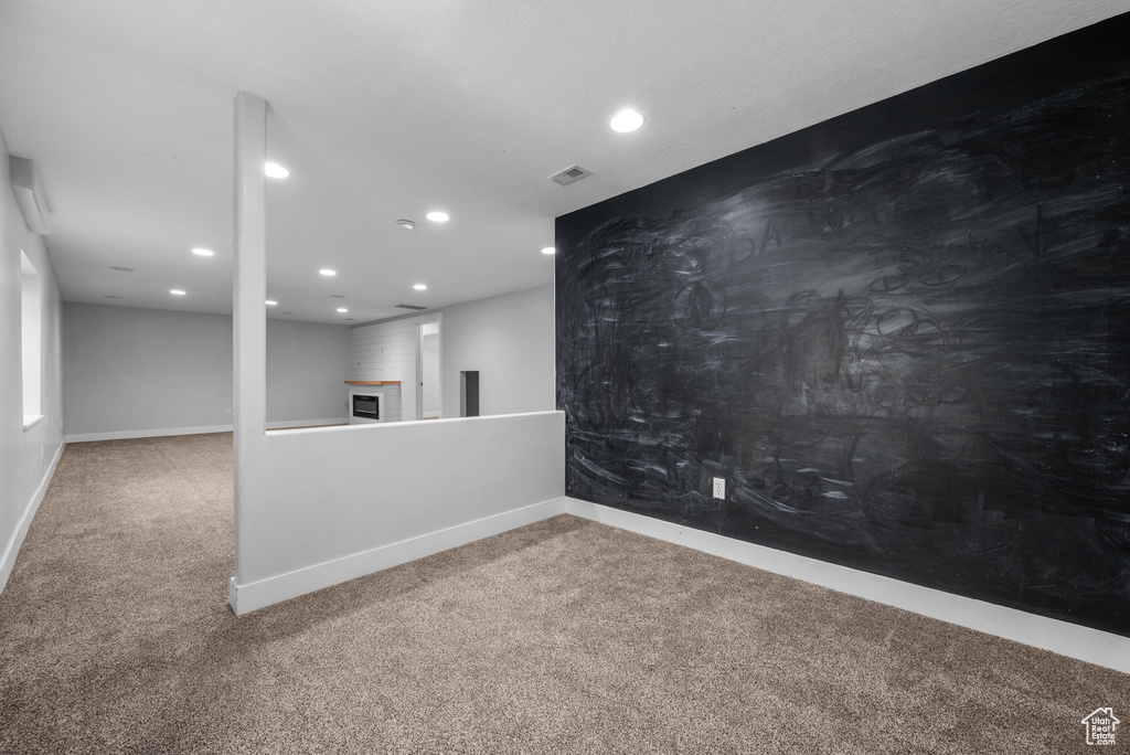 Carpeted spare room featuring recessed lighting, baseboards, and a fireplace