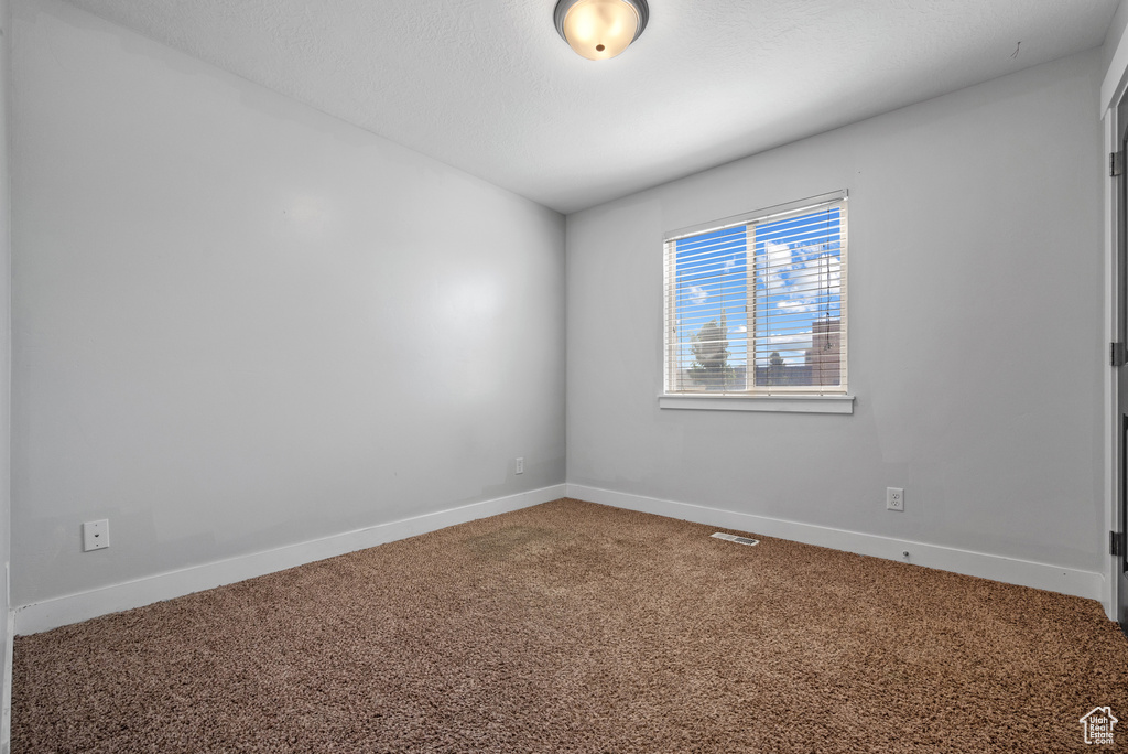 Spare room featuring carpet flooring and baseboards
