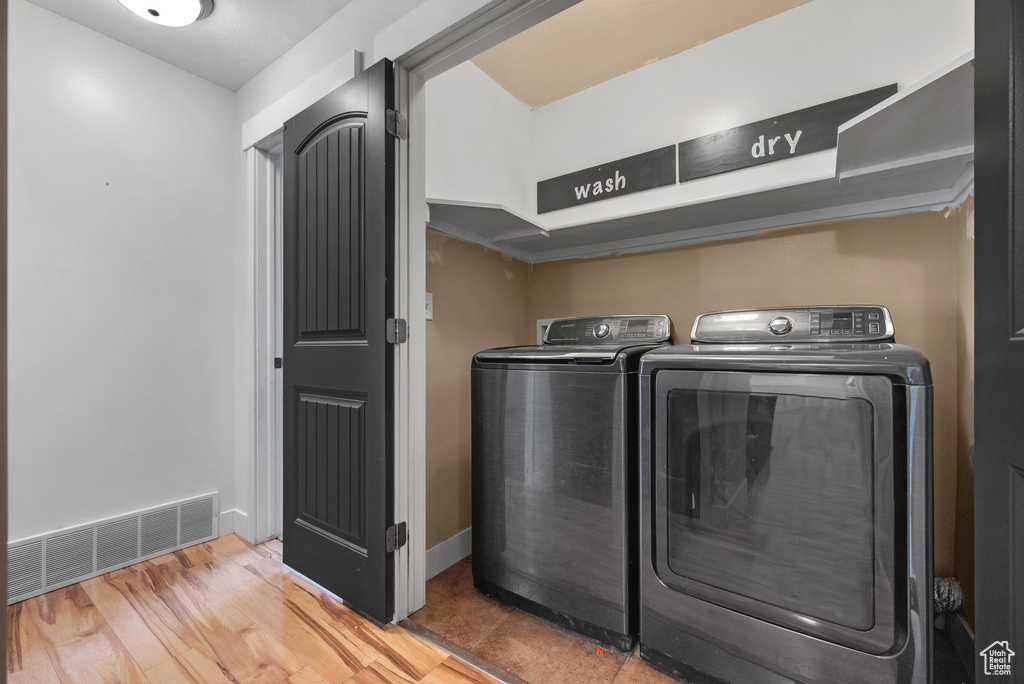 Laundry room featuring washing machine and clothes dryer, baseboards, and wood finished floors