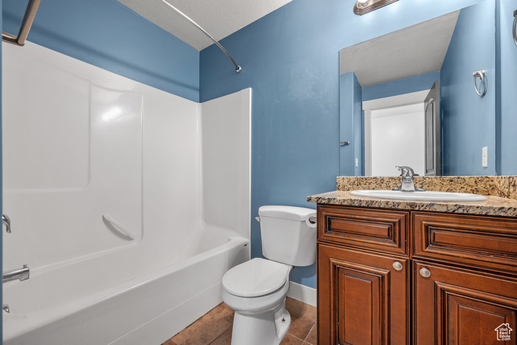 Bathroom featuring toilet, vanity, shower / bath combination, and tile patterned flooring