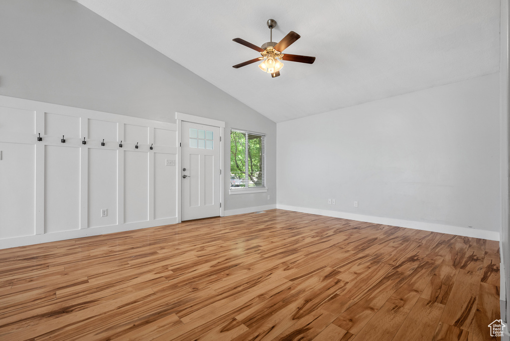 Unfurnished room featuring high vaulted ceiling, a ceiling fan, light wood-style floors, and baseboards