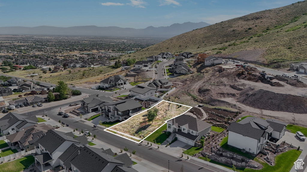 Aerial view of property and surrounding area featuring property boundaries highlighted, nearby suburban area, and a mountain backdrop