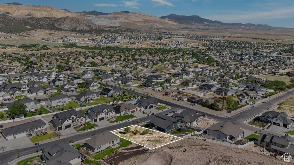 Aerial view of property and surrounding area featuring property boundaries highlighted, a mountain backdrop, and nearby suburban area