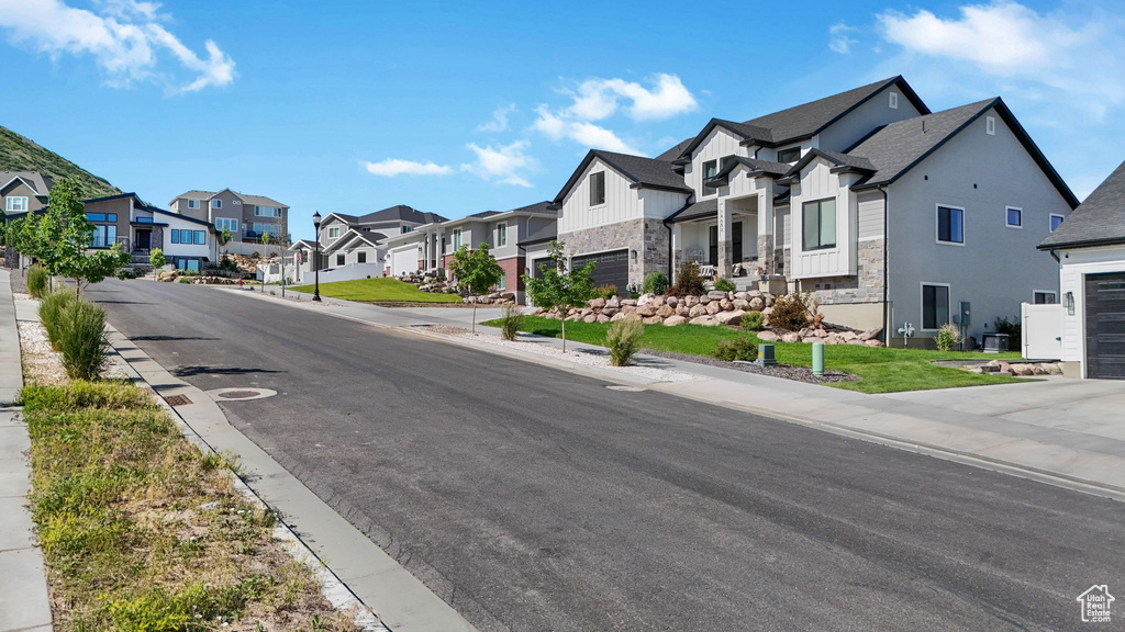 View of asphalt street featuring a residential view, sidewalks, and curbs