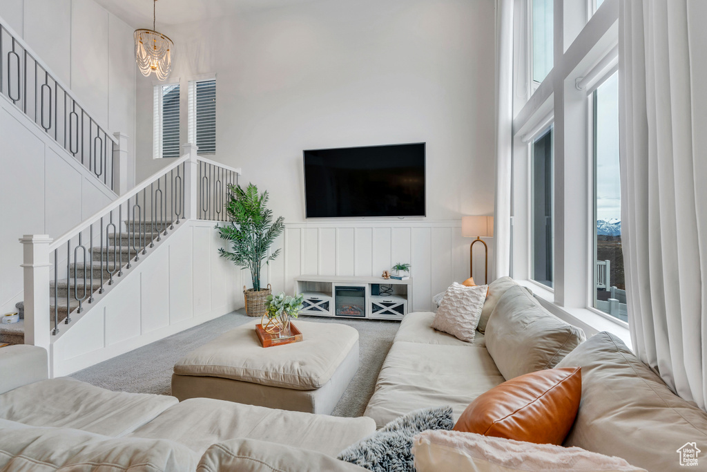 Carpeted living room with an inviting chandelier and a towering ceiling