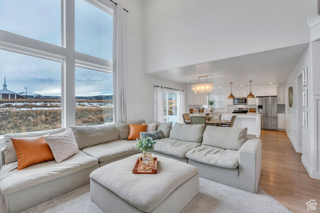 Living room featuring a towering ceiling, light hardwood / wood-style floors, and a chandelier