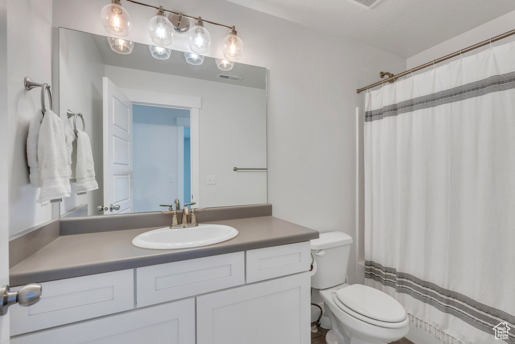 Bathroom with vanity, walk in shower, and toilet