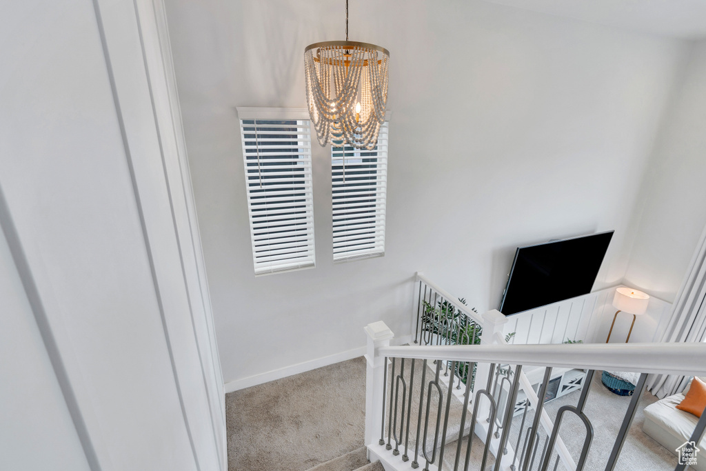 Stairs with carpet flooring and a chandelier