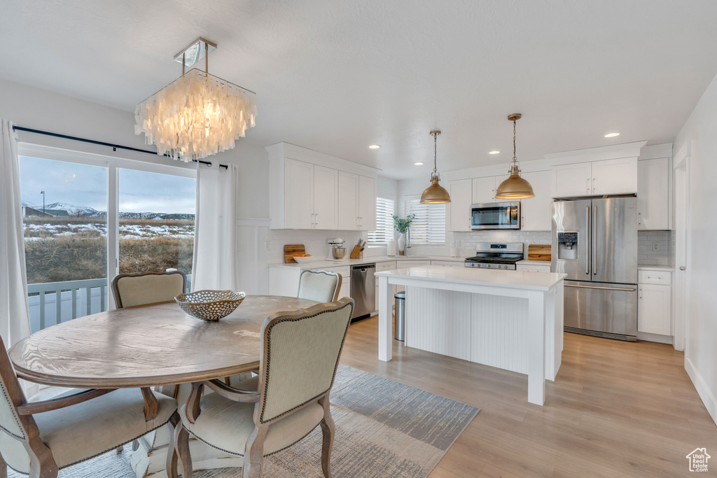 Dining room with an inviting chandelier and light hardwood / wood-style floors