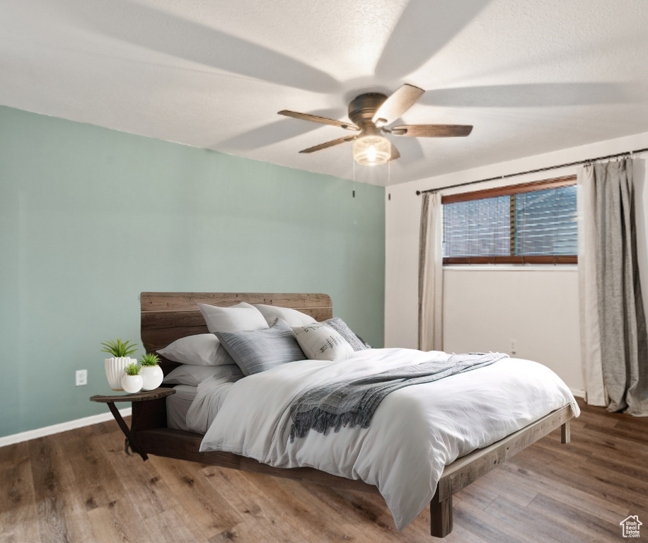 Bedroom with wood finished floors, ceiling fan, and baseboards