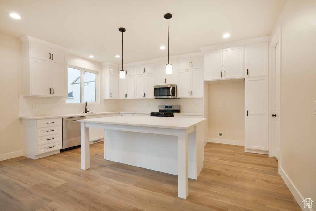 Kitchen featuring light countertops, appliances with stainless steel finishes, baseboards, and decorative backsplash