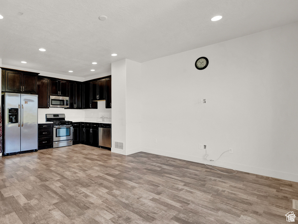 Kitchen featuring stainless steel appliances, light wood finished floors, recessed lighting, light countertops, and open floor plan