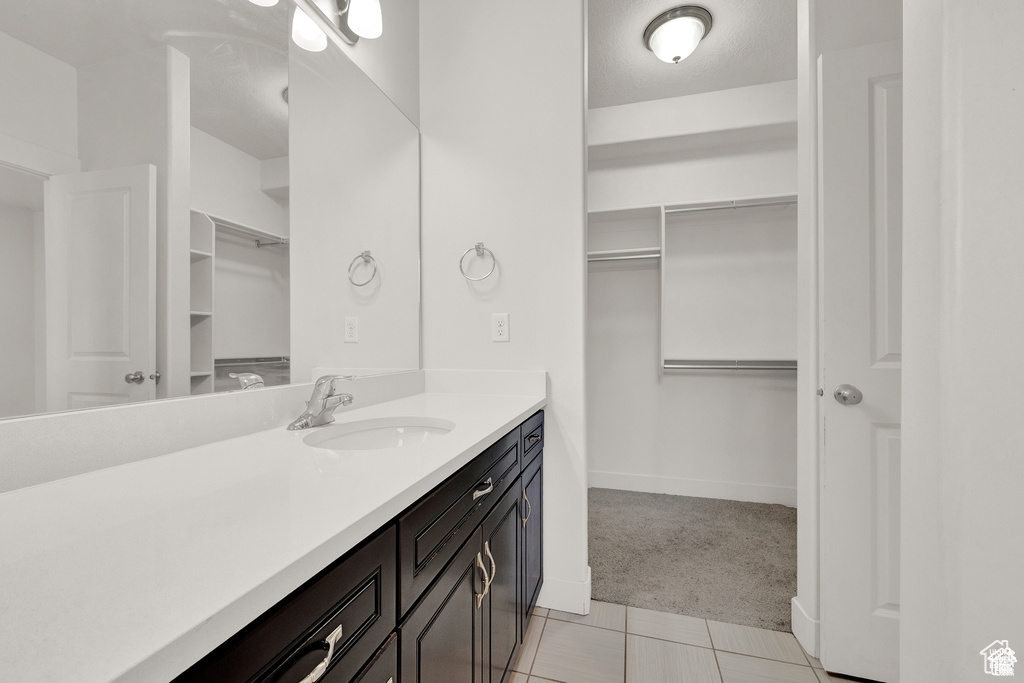 Bathroom featuring vanity, a spacious closet, and tile patterned floors