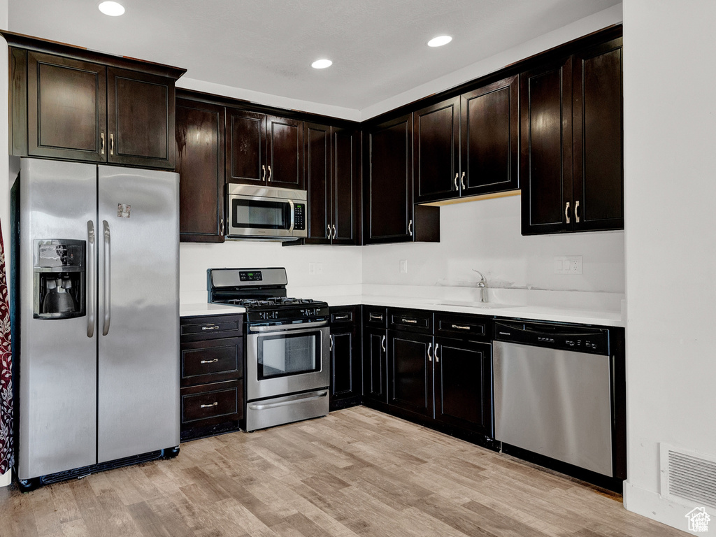 Kitchen with stainless steel appliances, light countertops, light wood finished floors, and recessed lighting