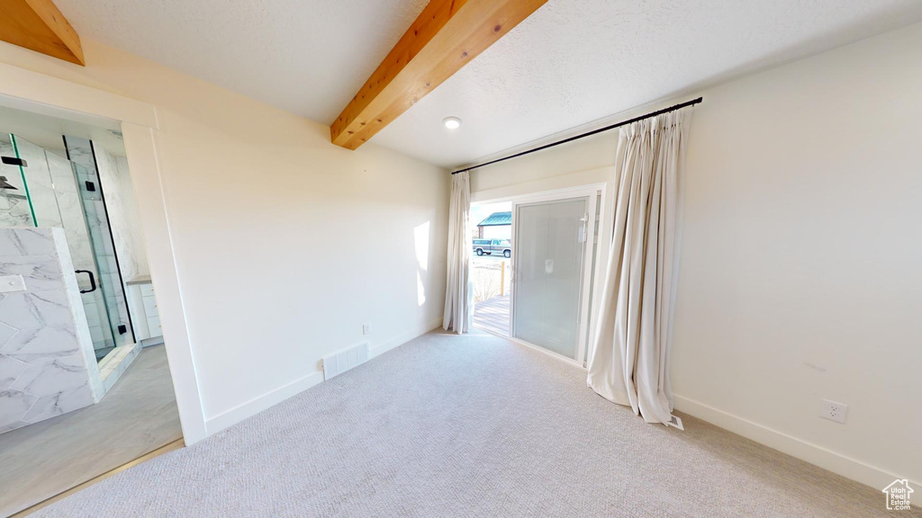 Spare room featuring light colored carpet and beam ceiling