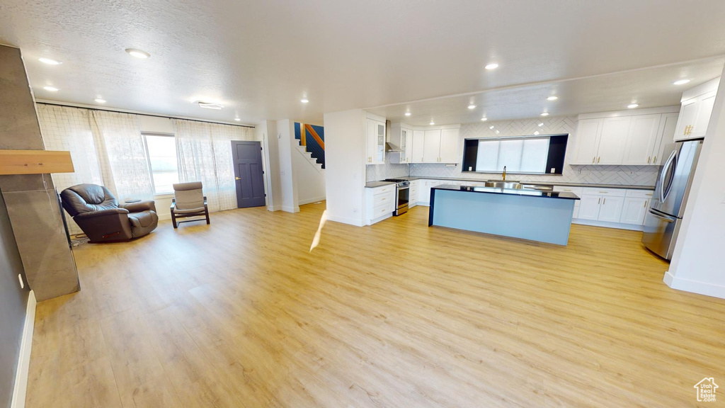 Kitchen featuring white cabinetry, appliances with stainless steel finishes, backsplash, and light wood-type flooring