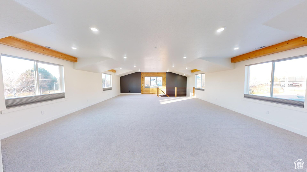 Interior space with light carpet and vaulted ceiling with beams
